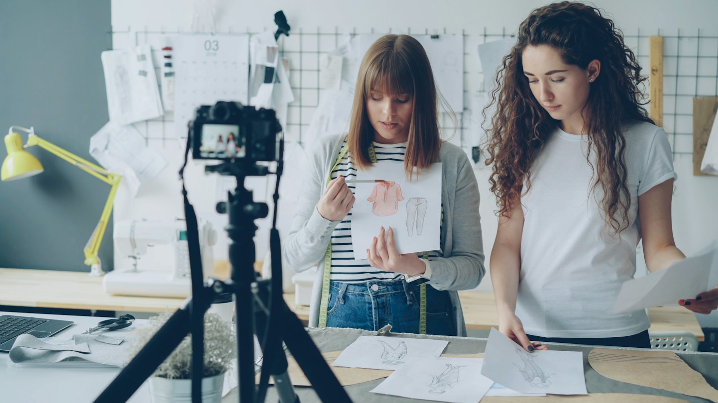 Two designers collaborate on fashion sketches in a bright studio.