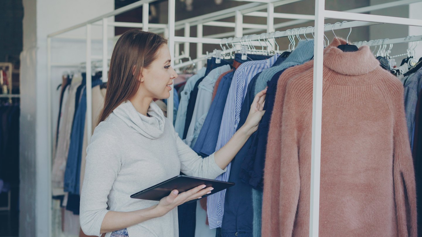 Woman browsing clothing on a rack in a store.